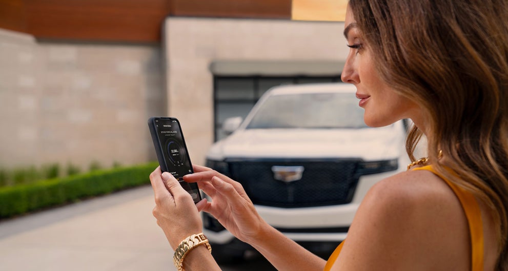 lady checking her mobile with a Cadillac vehicle background | House Cadillac in OWATONNA MN